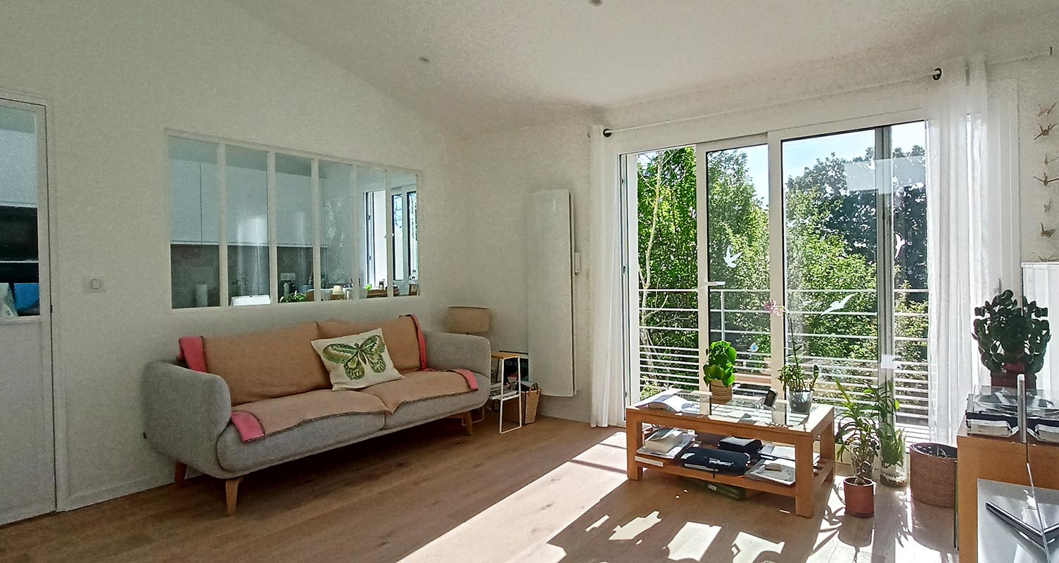 Vue du salon avec baie vitrée donnant sur un balcon